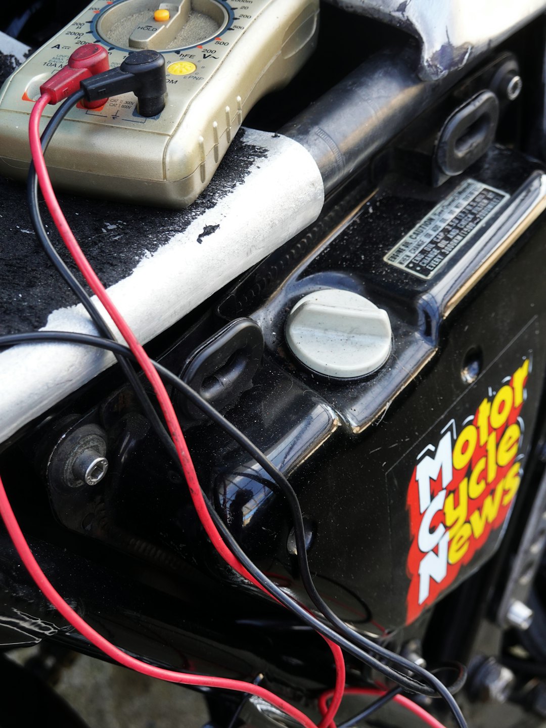 Multimetr cyfrowy testujący instalację elektryczną silnika motocykla.