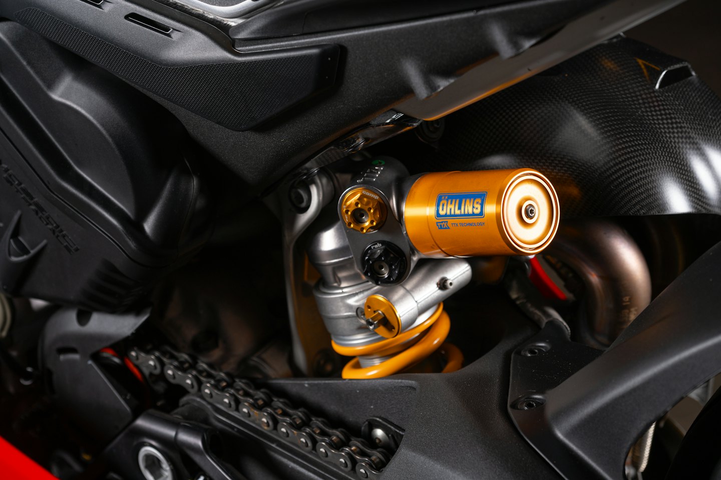 Złote i srebrne tylne zawieszenie motocyklowe Öhlins z żółtą sprężyną.