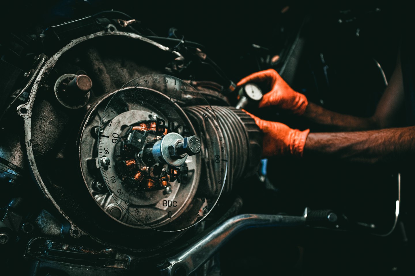 Ręce mechanika w rękawiczkach pracujące nad silnikiem motocykla.
